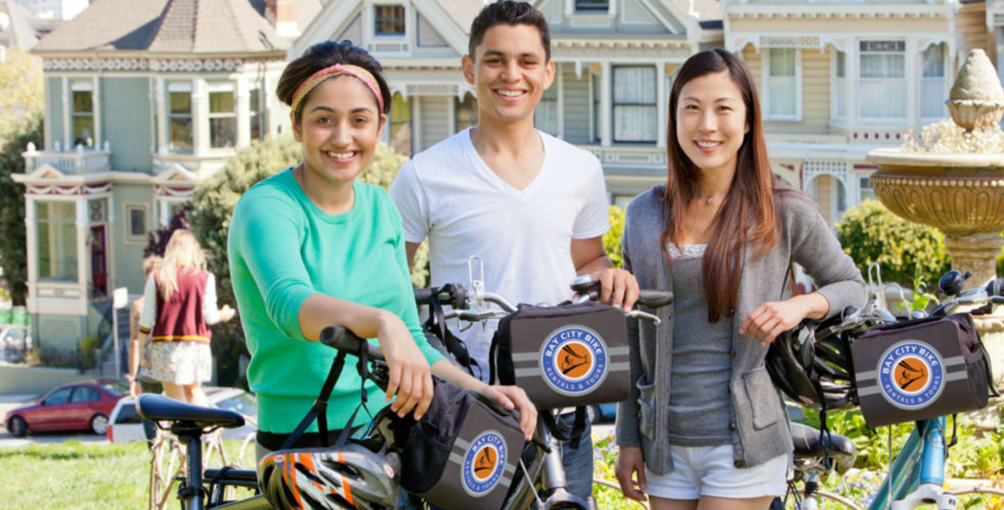 Three people smile in front of the Painted Ladies in San Francisco