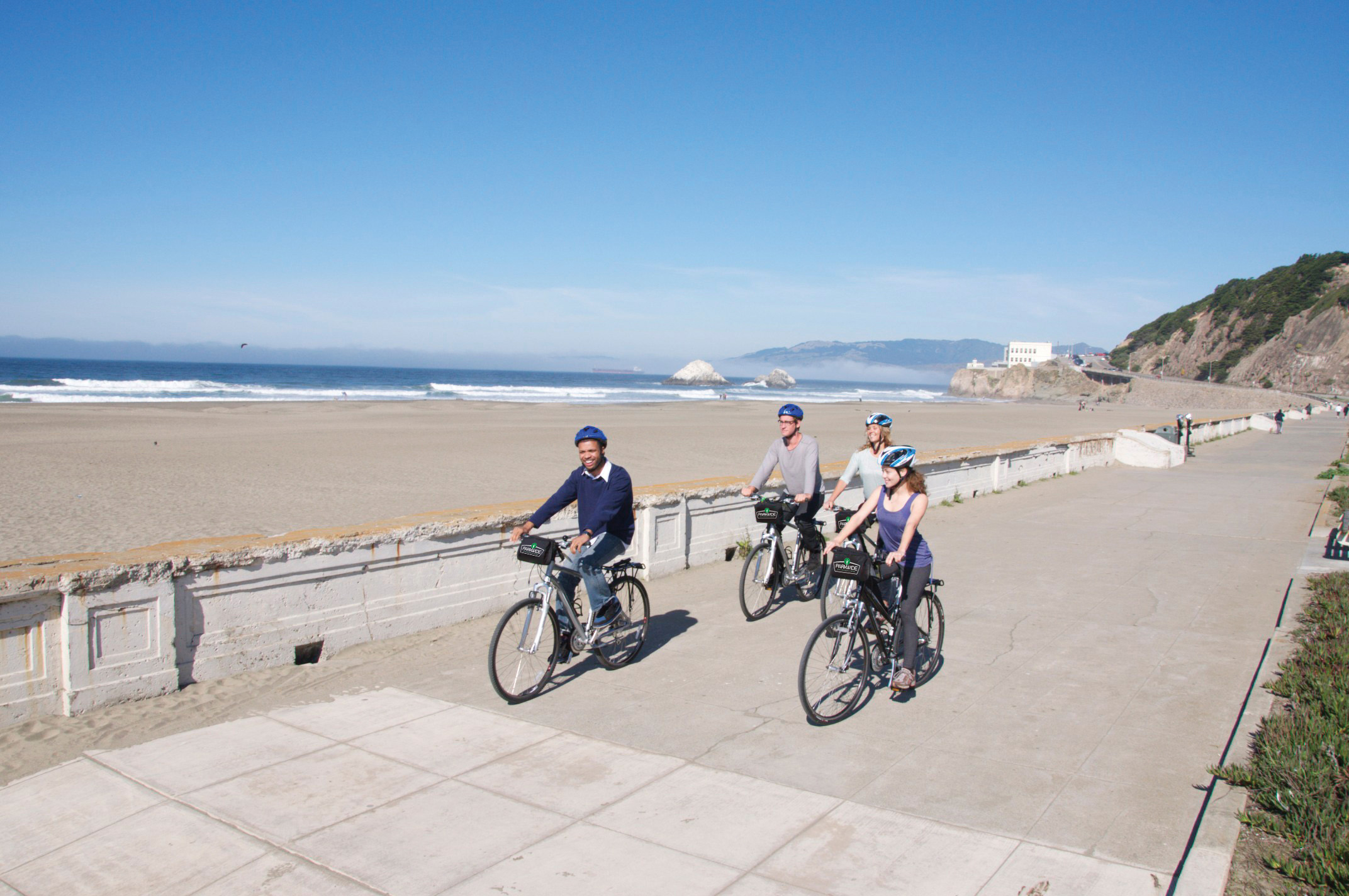 Four people ride bikes on the boardwalk in San Francisco