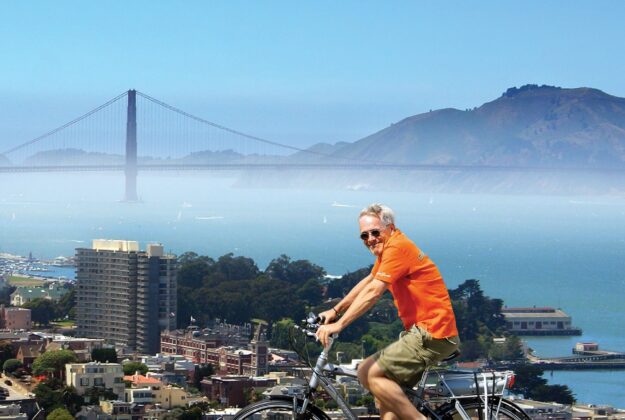 A man on a bike smiles while biking above San Francisco