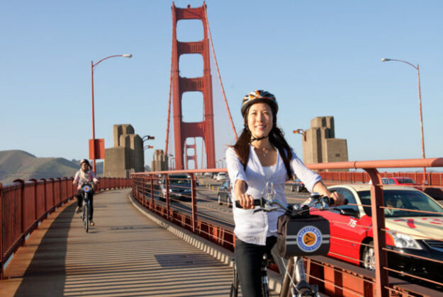 a woman rides a rented bicycle across the golden gate bridge