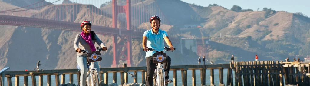 BRIDGE 16 1800px x 500px couple biking past golden gate bridge san francisco bike tours